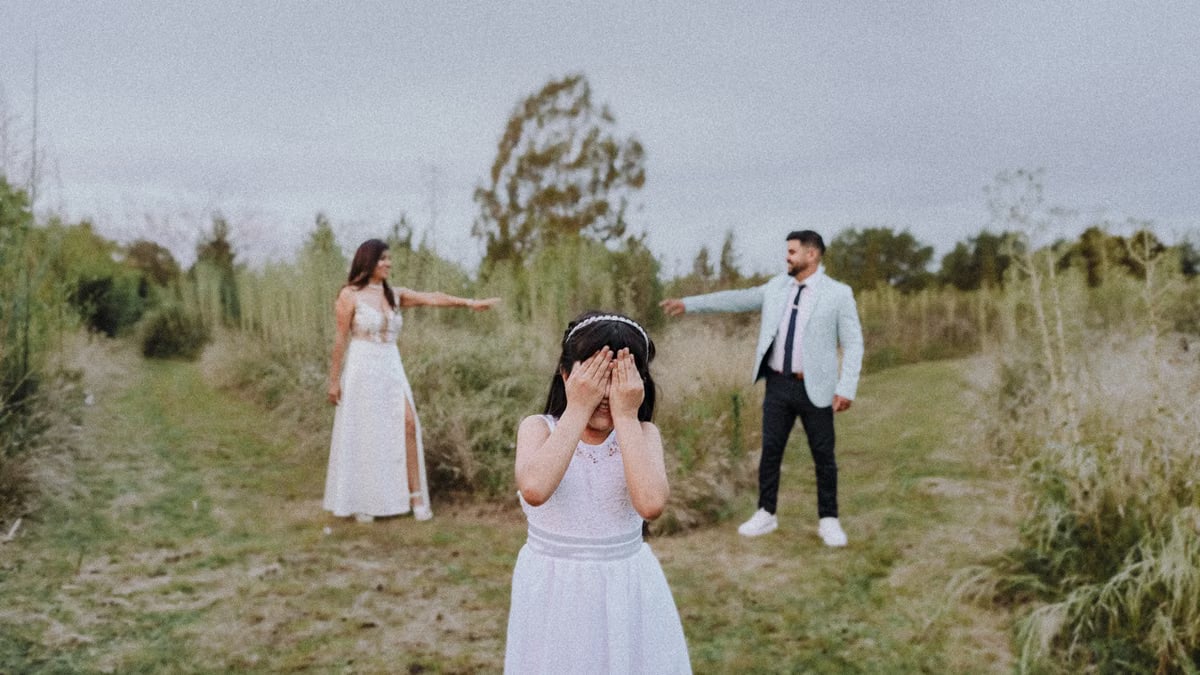 Family dressed in white having fun outdoors in a playful hide and seek moment.